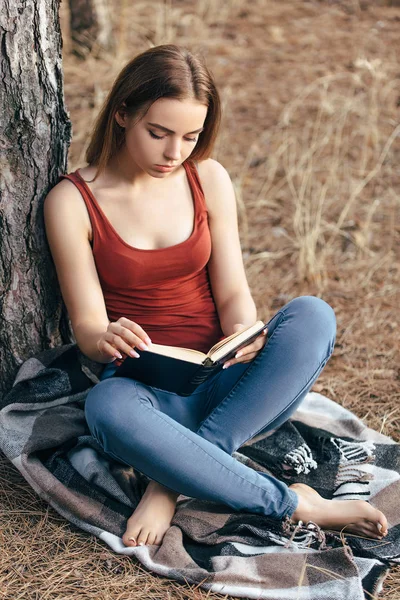 Женщина читает в природе под деревом — стоковое фото