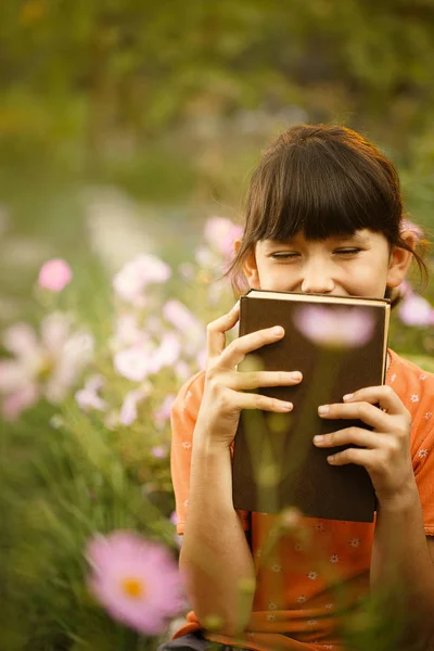 Schattig meisje leest buitenshuis op een zonnige dag, internationale alfabetiserings dag. — Stockfoto