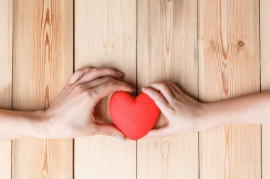 Ahşap arka planda kırmızı kalpli eller