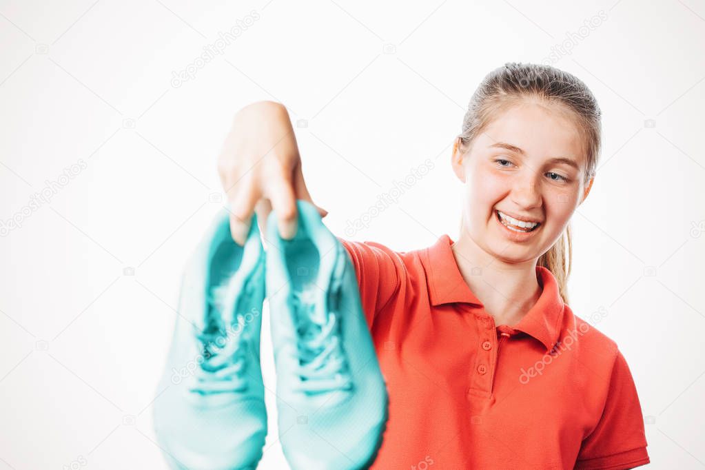 girl holds stinky sneakers and closes her hand with her nose