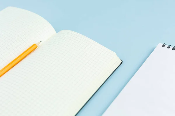 Open notebook with a pencil on blue background.