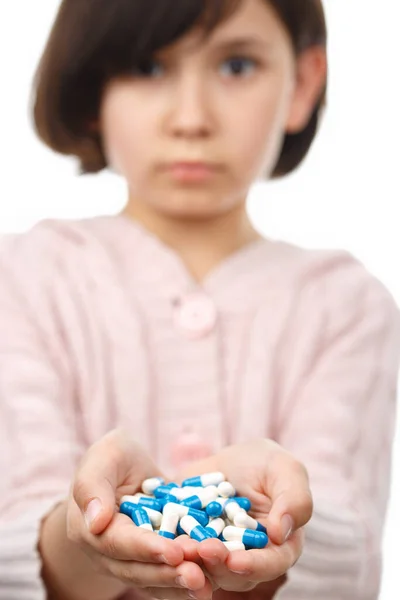 Ребенок держит горсть таблеток на белом фоне . — стоковое фото