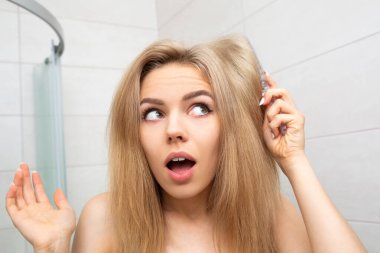 Banyodaki güzel kadın dağınık saçlara bakar..