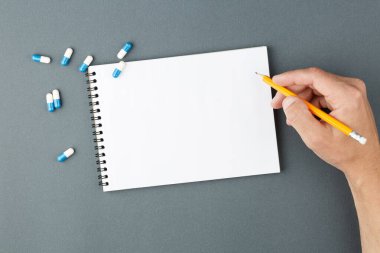 Kapsül haplı defter ve kalemli el..