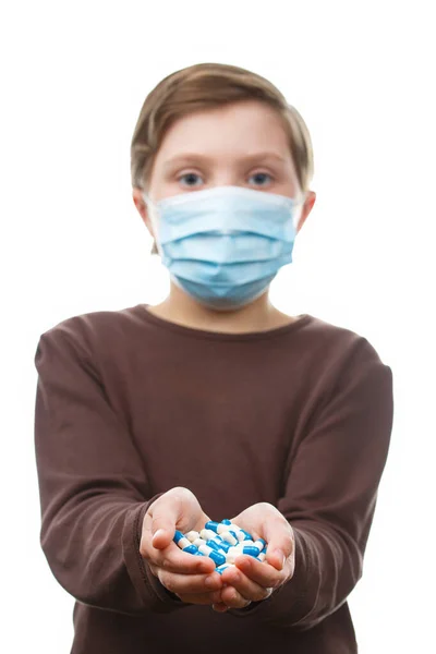 Criança em máscara médica contém um punhado de pílulas. — Fotografia de Stock