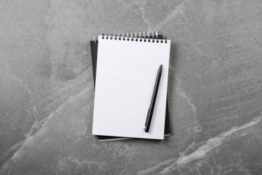 Gri mermer masa üzerinde kalem olan siyah defter