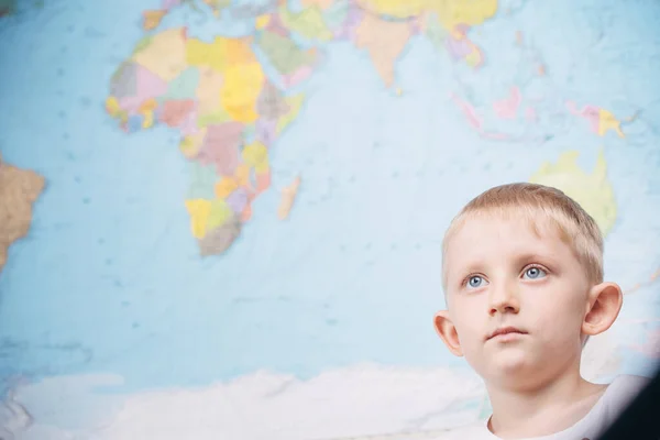 Kleine jongen op de achtergrond van een wereldkaart — Stockfoto