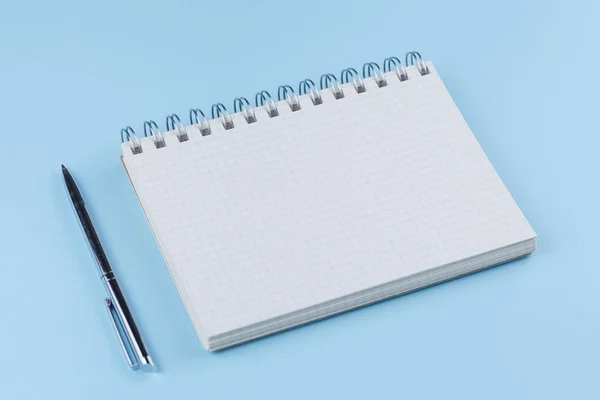 Caderno escolar com caneta em uma mesa azul vista superior — Fotografia de Stock