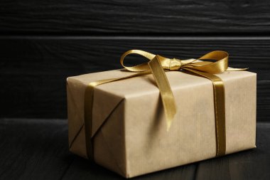 Siyah ahşap arka planda kurdeleli hediye kutusu