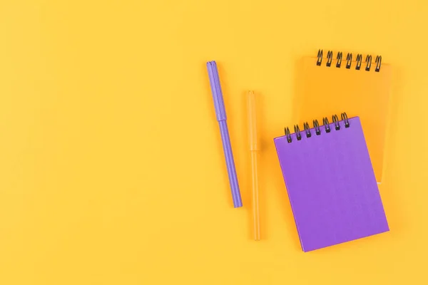 Closed notebooks with markers on yellow — Stock Photo, Image