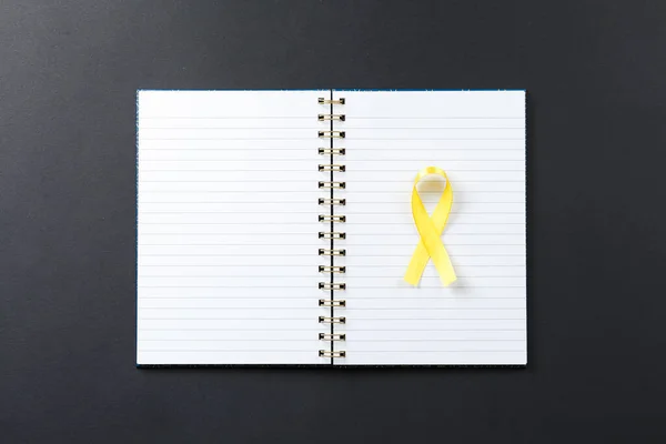 yellow cancer ribbon on notebook