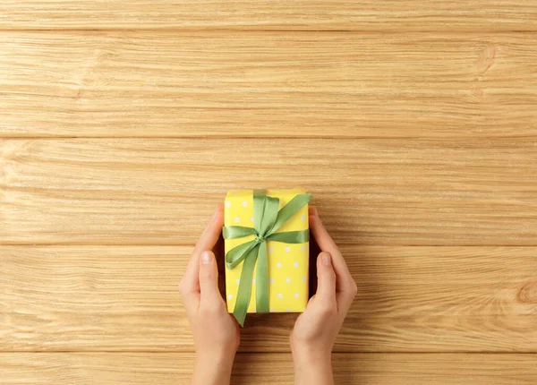 Caja de regalo en las manos sobre un fondo de madera — Foto de Stock