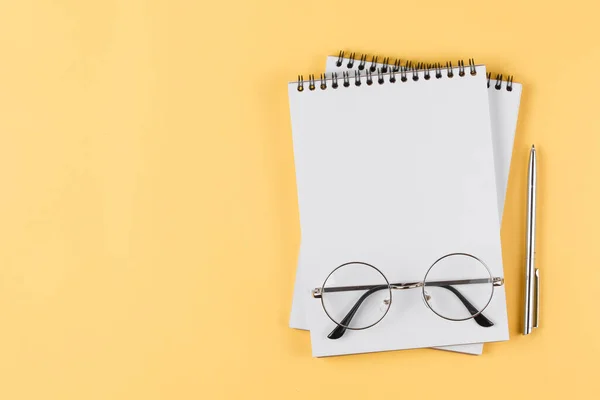 notebook with black pen and glasses