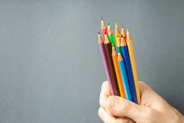 Lápices de colores en la mano sobre fondo gris — Foto de Stock