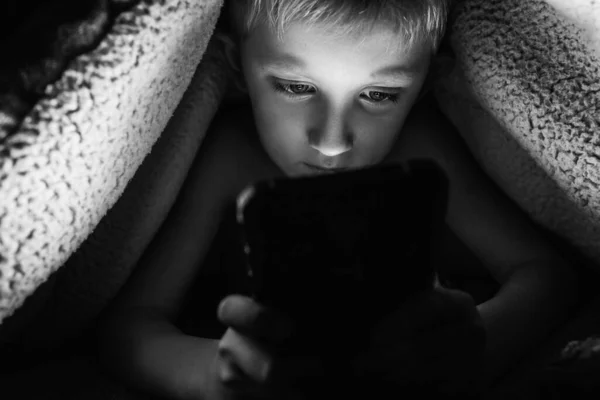 Jongen speelt games op een smartphone 's nachts — Stockfoto