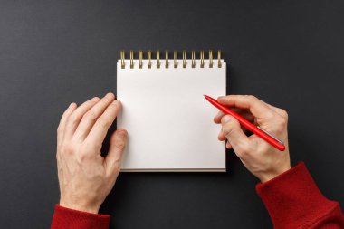 Elinde siyah kalem olan defter. 