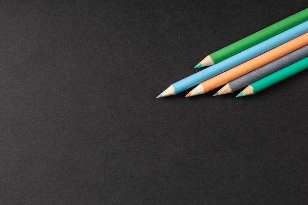 Lápices de colores en fila sobre un fondo negro — Foto de Stock