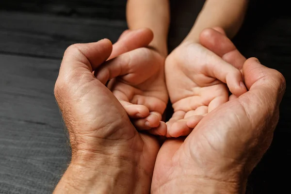 Les mains d'un homme âgé tenant la main d'un homme plus jeune — Photo