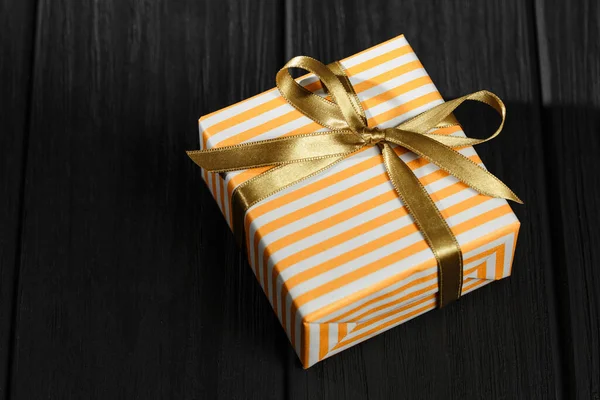 Caja de regalo con cinta sobre fondo de madera negro — Foto de Stock