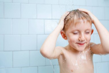 Küçük çocuk duşta yıkanıyor.
