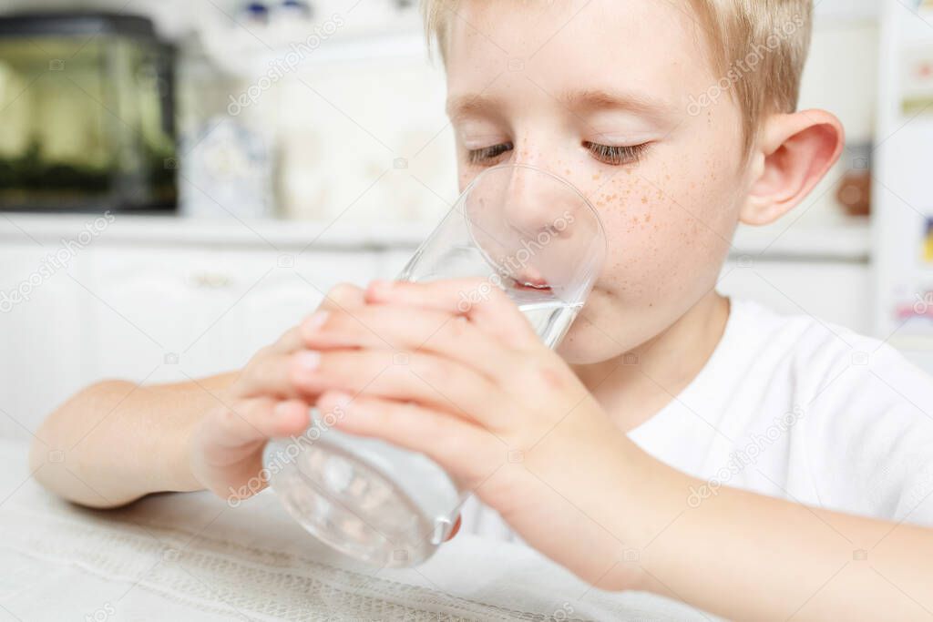 little boy drinks clean water from glass