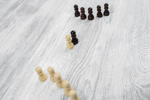 Black and white pawns on a wooden table