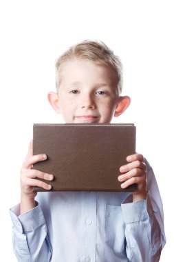 Çocuk yüzünü kitapların arkasına saklar.