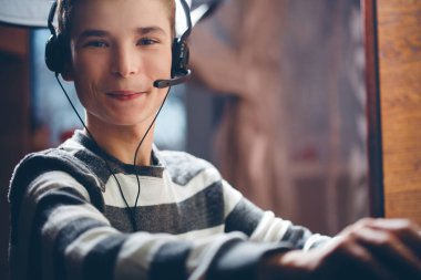 Kulaklıklı, mikrofonlu çocuk dizüstü bilgisayar çalıyor.