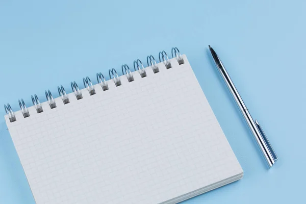 Caderno escolar com caneta em uma mesa azul vista superior — Fotografia de Stock