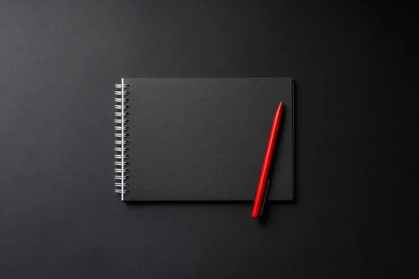 Блокнот з червоною ручкою на чорному фоні — стокове фото