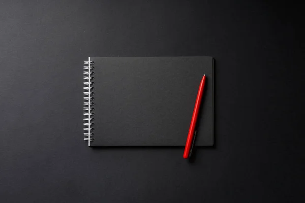 Cuaderno con pluma roja sobre fondo negro — Foto de Stock