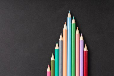 Siyah arkaplanda renkli kalemler satırda