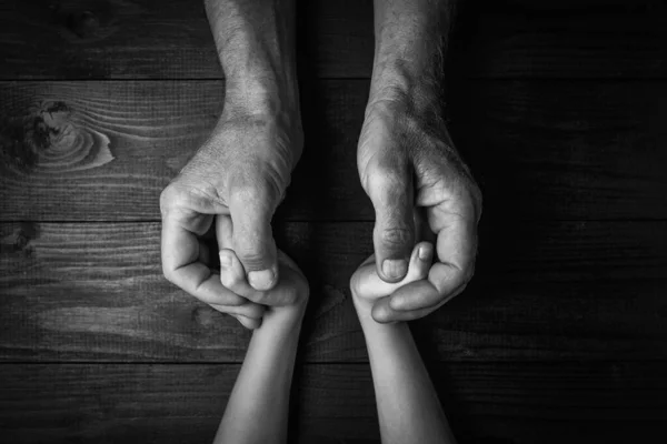 Mãos de um homem idoso segurando a mão de um jovem — Fotografia de Stock