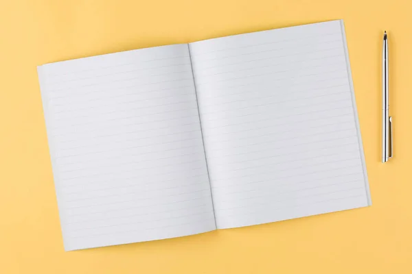 Cuaderno con pluma negra sobre fondo amarillo — Foto de Stock