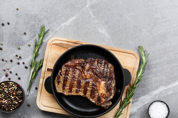 fried steak in pan on gray marble table top view