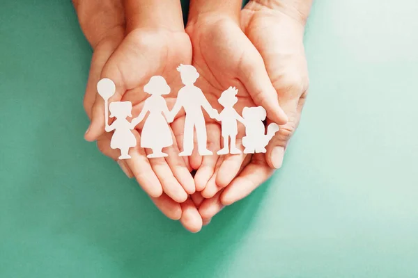 Yetişkin ve çocuk elleri kağıt aile kesimi, aile evi, evlat edinme, koruyucu aile.