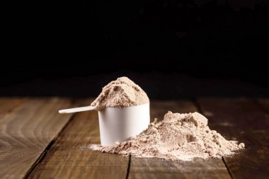 Tahta masada milkshake hazırlamak için bir kepçe süt proteini ölçüyorum..