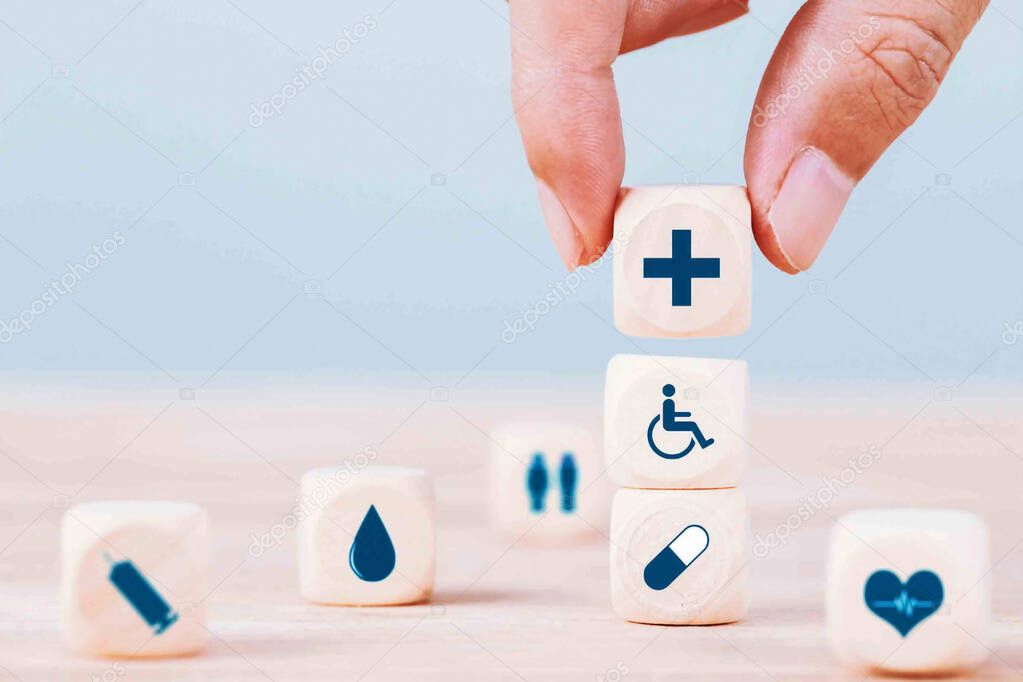 Hand chooses a emoticon icons healthcare medical symbol on wooden block , healthcare and medical insurance concept 