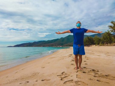Coronavirus COVID 19. Genç ve güzel bir adam karantina sırasında sabah deniz kenarında spor egzersizleri yapıyor. Yüz maskesi korumalı cerrahi sterilize yaşam