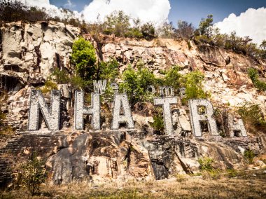 Nha Trang kelimesi beton harflerden yapılmıştır. Nha Trang Vietnam 'ın ünlü deniz turistleri şehridir. Dağlar, kayalar, arka planda mavi gökyüzü. Hoan Cau İngilizcede Küreseldir