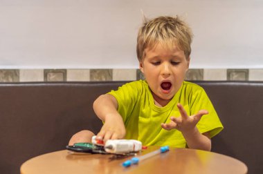 Çocuk geri dönüştürülmüş malzemelerle oyuncak yaparken yanmış parmağına zarar verdi. Sıcak eritilmiş yapıştırıcı tabancası kullanarak plastik saman. Yaratıcılık ve el sanatları yaparken güvensizliği desteklemek. Karantina sırasında yaratıcı eğlence
