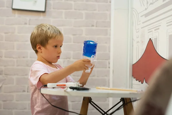 재활용 된 플라스틱 병으로 만든 DIY 장난감을 직접 만들어 보 세요. 뜨거운 녹인 접착제 총을 사용 한 컵을 사용 해서 말이죠. 창의력을 지지하고, 수공예를 지지 합니다. 집에 격리되어 있는 동안 실내에서 아이들을 위한 창의적 인 여가 시간은 시원하다 — 스톡 사진