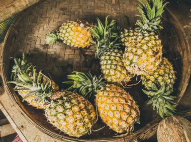 Örülmüş sepet içinde ananas yığını. Piyasada taze taze organik meyve topladım. Smoothie pişirmek, ev yapımı bahçe işleri ve sağlıklı gıda konsepti, güçlü bağışıklık için vitaminler.
