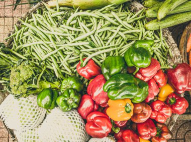 Yakın çekim yığını, yerel Asya çiftçi pazarında kırmızı yeşil dolma biber, yeşil fasulye ve brokoli. Yemek pişirme ve sağlıklı gıda konsepti, güçlü bağışıklık için vitaminler, iyi beslenme değeri
