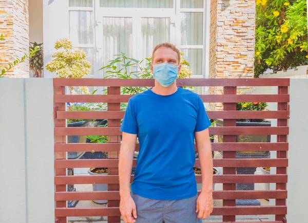 Portrait of guy with a medical mask. Outside walking in the garden near modern summer house. He wants to breathe, wait for the end of quarantine Covid19 isolation and beginning of normal life again