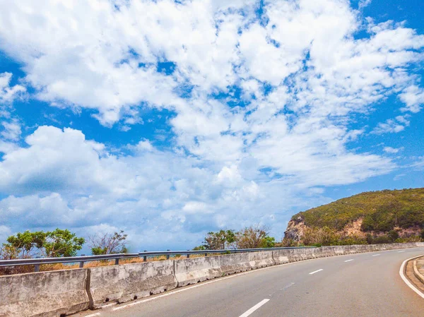 Suchý asfalt prázdná auto zakřivená silnice s betonovou bariérou a značící čáry v horách za slunečného letního dne s modrou oblačnou oblohou. Cesta autem koncepce pozadí — Stock fotografie