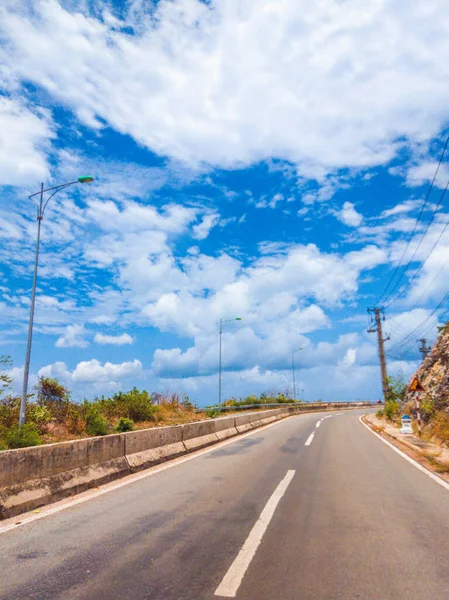 Suchý asfalt prázdná auto zakřivená silnice s betonovou bariérou a značící čáry v horách za slunečného letního dne s modrou oblačnou oblohou. Cestování autem koncepce pozadí. Svislý formát příběhů — Stock fotografie