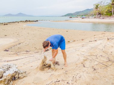 Eldivenli adam denizi kirleten plastik torbalar alıyor. İnsan yapımı kirlilik ve çevresel kirliliğin yol açtığı kumsala çöp dökme sorunu, konsept olarak gönüllü temizleme kampanyası
