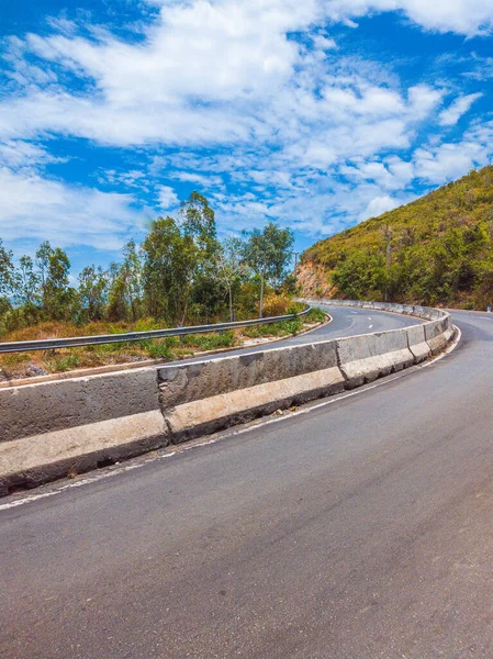 Suchý asfalt prázdná auto zakřivená silnice s betonovou bariérou a značící čáry v horách za slunečného letního dne s modrou oblačnou oblohou. Cestování autem koncepce pozadí. Svislý formát příběhů — Stock fotografie