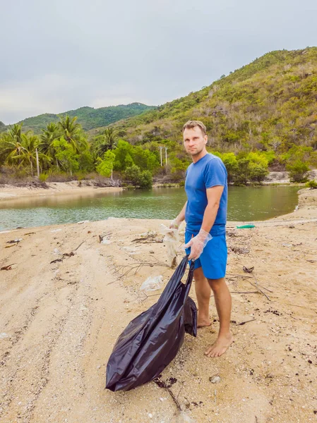 Manusia dalam sarung tangan mengambil kantong plastik yang mencemari laut. Masalah tumpah sampah sampah di pasir pantai disebabkan oleh polusi buatan manusia dan lingkungan, kampanye untuk membersihkan diri secara sukarela dalam konsep — Stok Foto